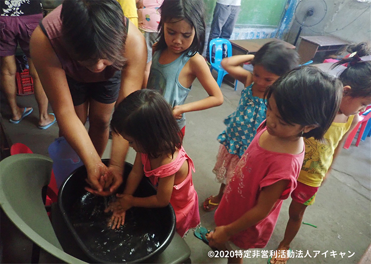子どもたちに正しい手洗いの仕方を教える地域住民