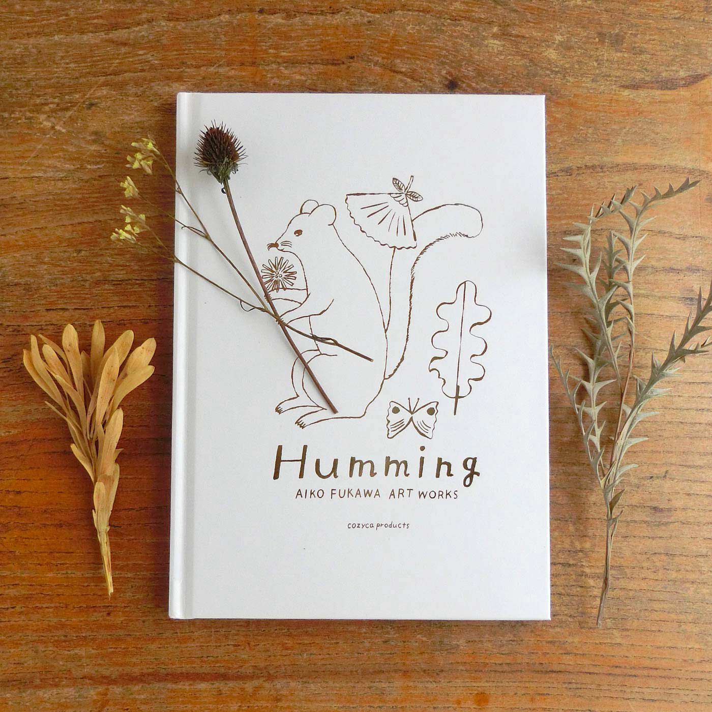 フェリシモの雑貨Kraso|とびきりのかわいさ！ 布川愛子　作品集「Humming（ハミング）」|表紙には、タイトル「Humming（ハミング）」が、金色ではく押しされています。ていねいで美しいつくりの作品集です。